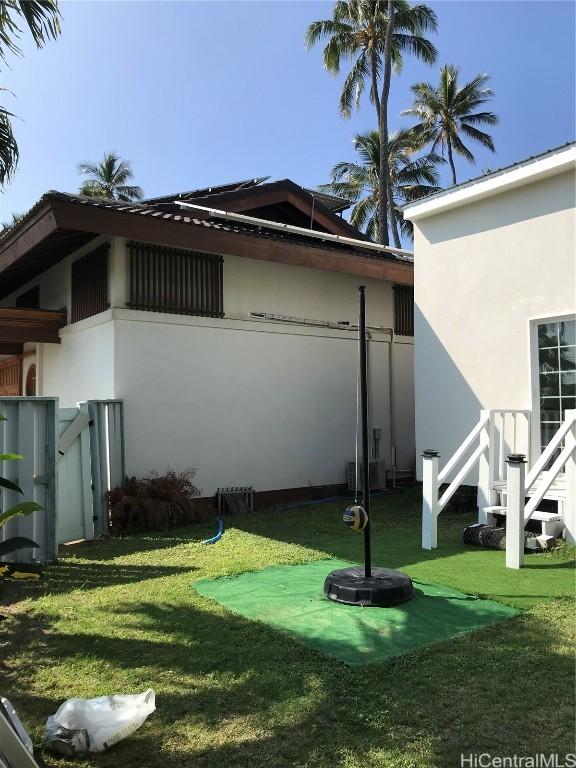 view of side of home featuring a yard, fence, and stucco siding