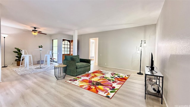 living area with baseboards, ceiling fan, and wood finished floors