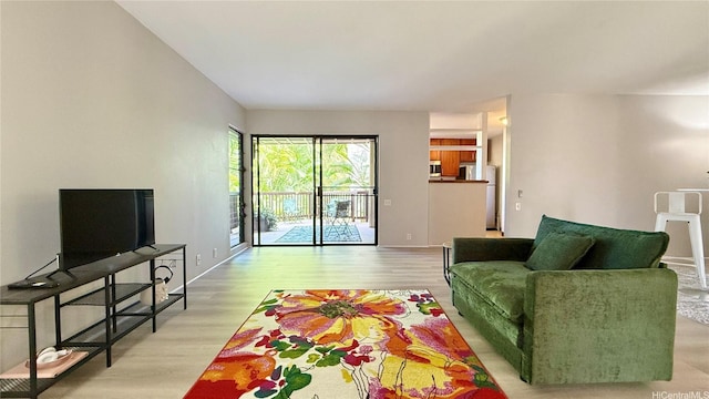 living area featuring baseboards and light wood-style flooring