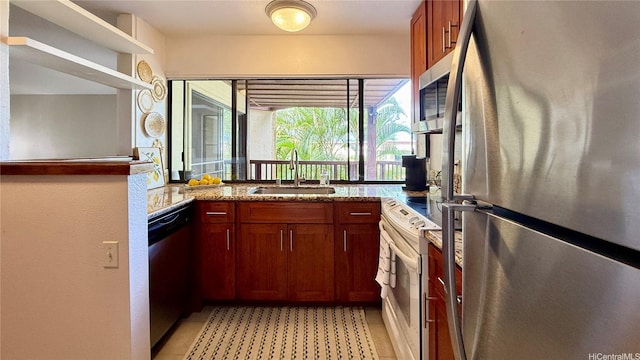 kitchen featuring light tile patterned flooring, light stone countertops, brown cabinets, a sink, and stainless steel appliances