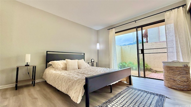 bedroom with baseboards, wood finished floors, and access to exterior