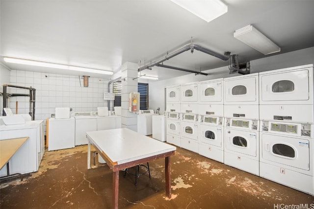 common laundry area featuring washing machine and dryer, stacked washer and clothes dryer, and tile walls