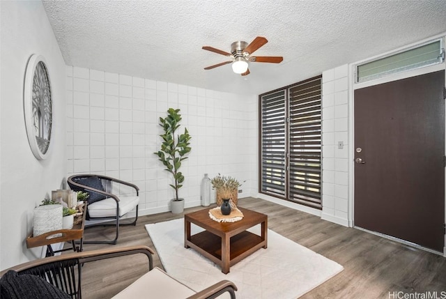 living area featuring tile walls, a textured ceiling, and wood finished floors