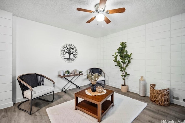 sitting room featuring ceiling fan, a textured ceiling, baseboards, and wood finished floors