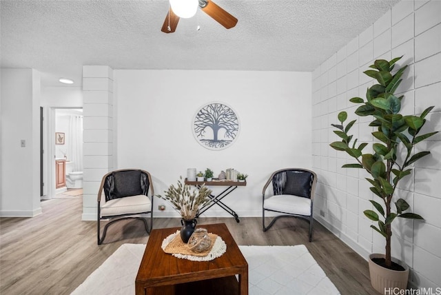 sitting room featuring a textured ceiling, wood finished floors, a ceiling fan, and baseboards