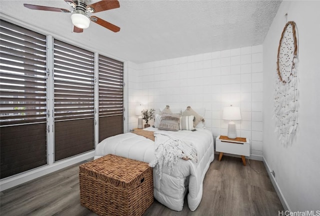 bedroom featuring a ceiling fan, a textured ceiling, baseboards, and wood finished floors