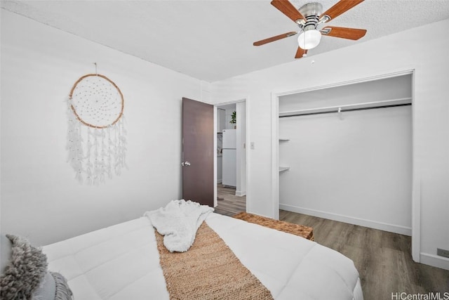 bedroom with ceiling fan, wood finished floors, baseboards, a closet, and freestanding refrigerator