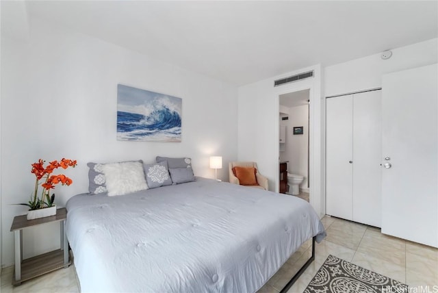 bedroom featuring light tile patterned floors, a closet, visible vents, and connected bathroom