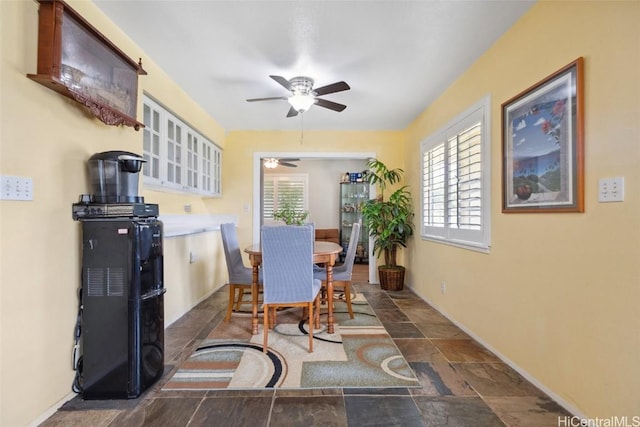 dining room with stone finish floor, a ceiling fan, and baseboards