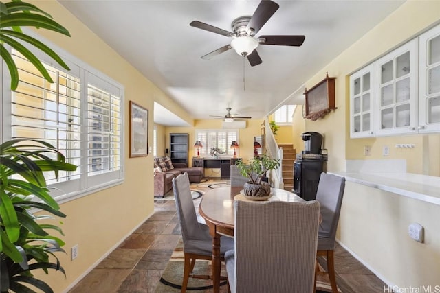 dining space featuring baseboards, stone tile floors, and ceiling fan