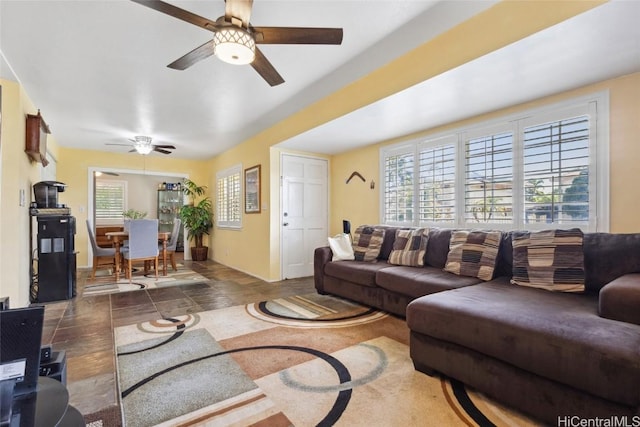 living area featuring a wealth of natural light, stone finish flooring, and a ceiling fan