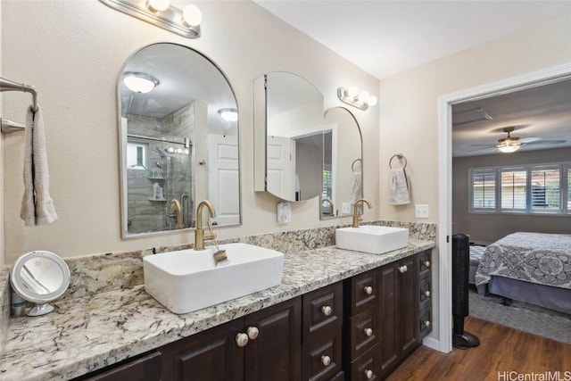 bathroom with double vanity, wood finished floors, a stall shower, and a sink