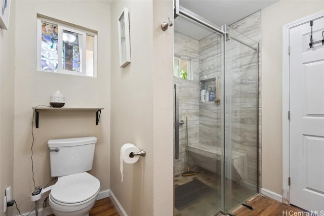 full bath with a stall shower, toilet, baseboards, and wood finished floors