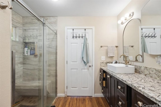 full bathroom with baseboards, a shower stall, wood finished floors, and vanity