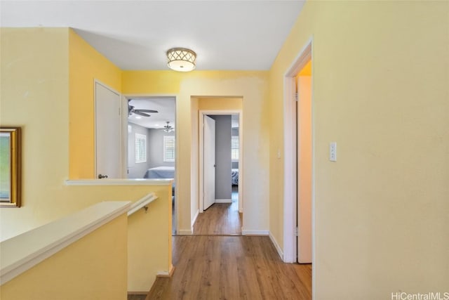 hallway featuring an upstairs landing, baseboards, and light wood-style floors