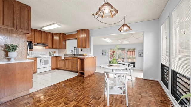 kitchen featuring under cabinet range hood, a textured ceiling, light countertops, and white range with electric stovetop