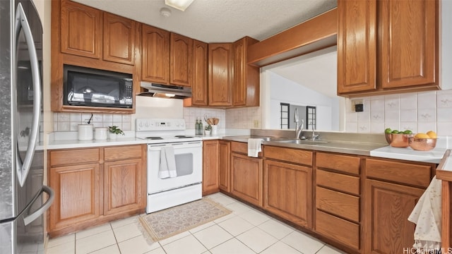 kitchen featuring white range with electric cooktop, stainless steel refrigerator, black microwave, under cabinet range hood, and brown cabinets