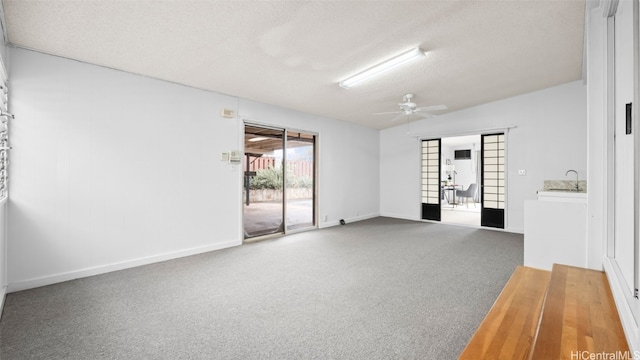 empty room with a textured ceiling, baseboards, carpet floors, and ceiling fan