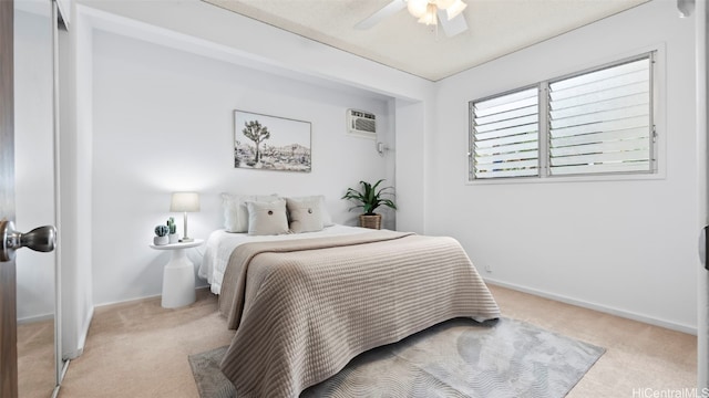 bedroom featuring light colored carpet, a wall mounted AC, baseboards, and ceiling fan