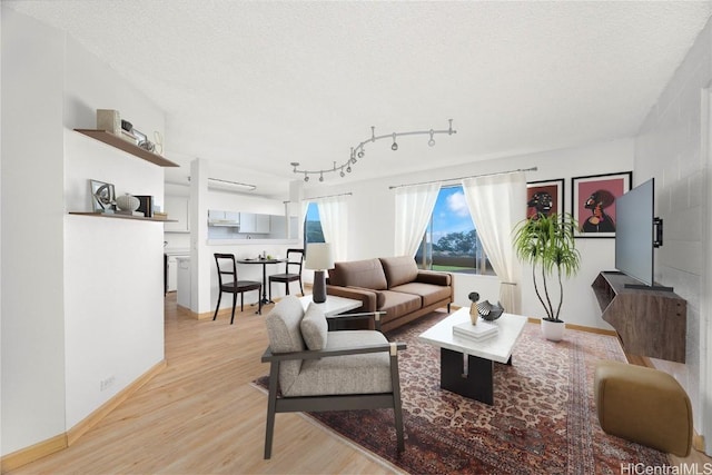 living area with light wood-style flooring, baseboards, and a textured ceiling