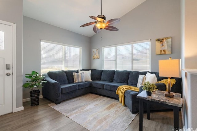 living area with vaulted ceiling, light wood finished floors, a wealth of natural light, and a ceiling fan