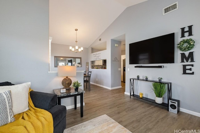 living area featuring visible vents, a notable chandelier, baseboards, and wood finished floors