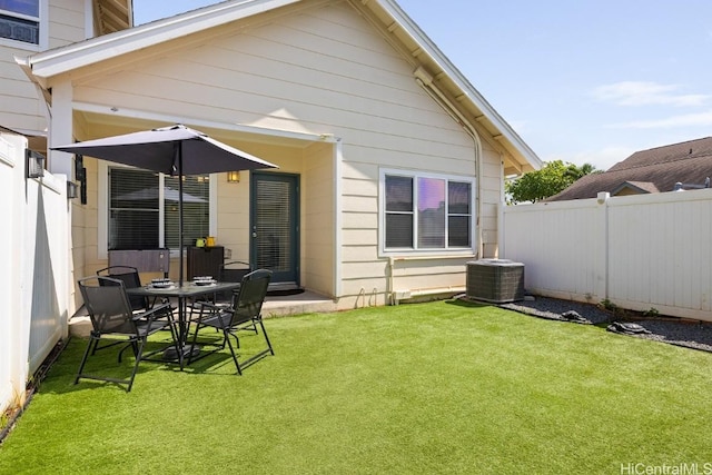 back of property featuring central AC, a lawn, and fence