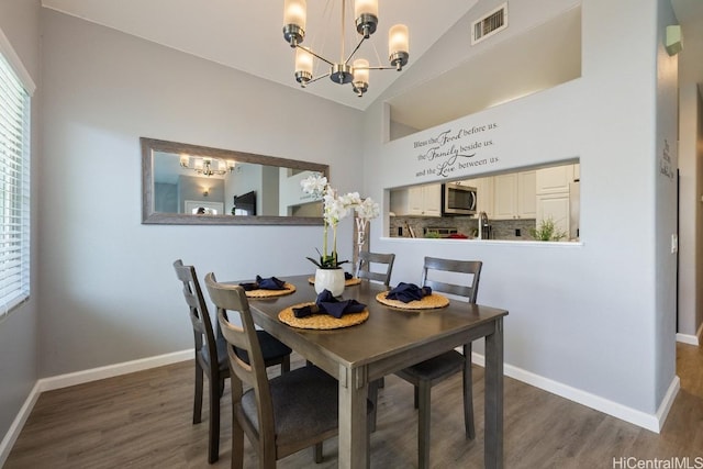 dining area featuring lofted ceiling, visible vents, a notable chandelier, and baseboards