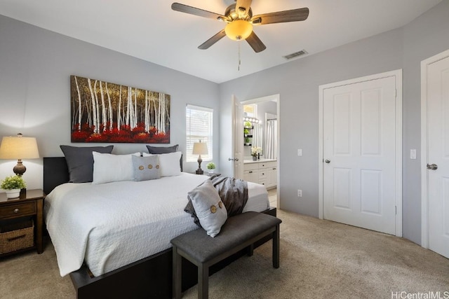 bedroom featuring ceiling fan, ensuite bath, visible vents, and light colored carpet