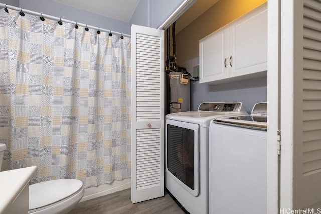 laundry room with washer and dryer, water heater, and wood finished floors