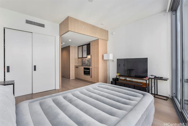 bedroom featuring light wood-style flooring, visible vents, and a closet