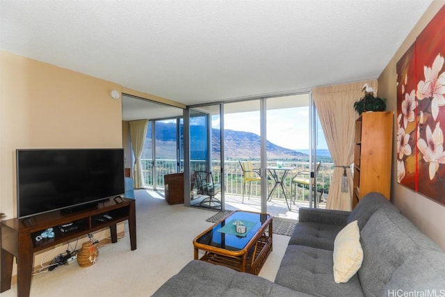 carpeted living area with expansive windows, a mountain view, and a textured ceiling