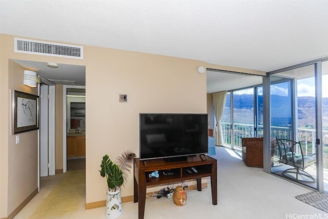 living room with carpet floors, a wall of windows, visible vents, and baseboards