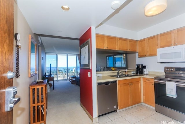 kitchen with stainless steel appliances, light tile patterned flooring, a sink, and light countertops