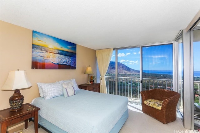 bedroom featuring expansive windows, carpet flooring, a mountain view, and access to exterior