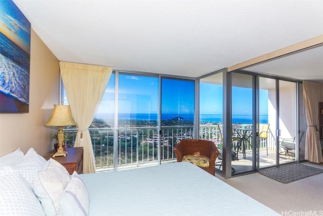 bedroom featuring access to outside, a wall of windows, a water view, and carpet floors