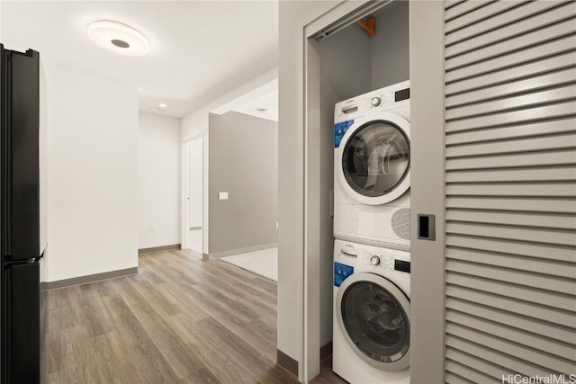 washroom with stacked washer and dryer, baseboards, laundry area, and wood finished floors