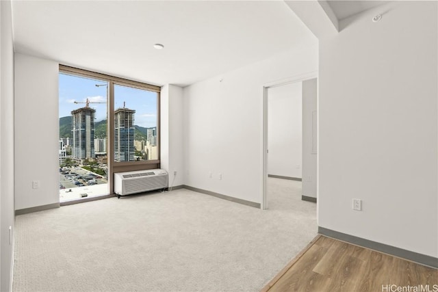 spare room featuring a wall unit AC, baseboards, and floor to ceiling windows