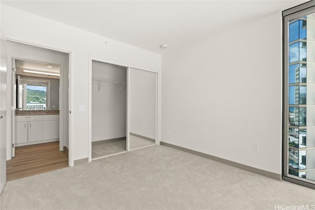 unfurnished bedroom featuring light carpet, baseboards, and a closet