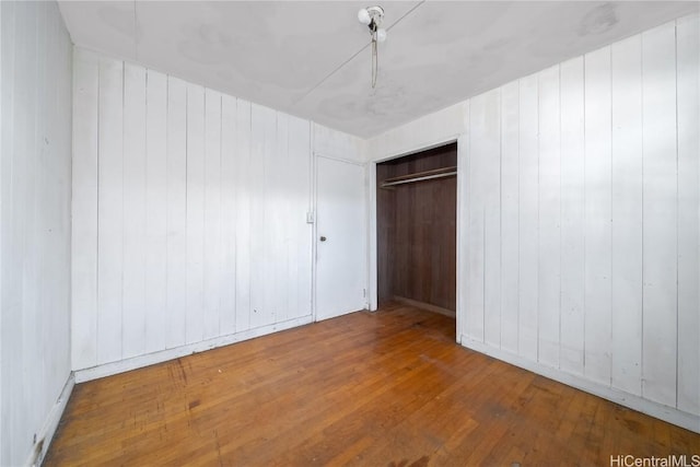 unfurnished bedroom with hardwood / wood-style floors, a closet, and a ceiling fan