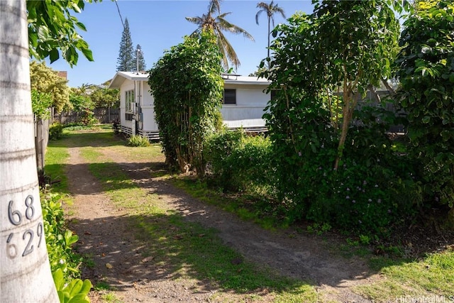 exterior space with entry steps, dirt driveway, and fence