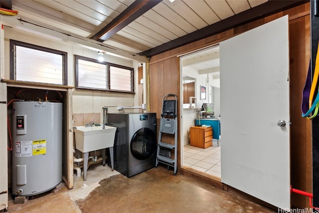 washroom featuring washer / dryer, water heater, laundry area, and wood walls