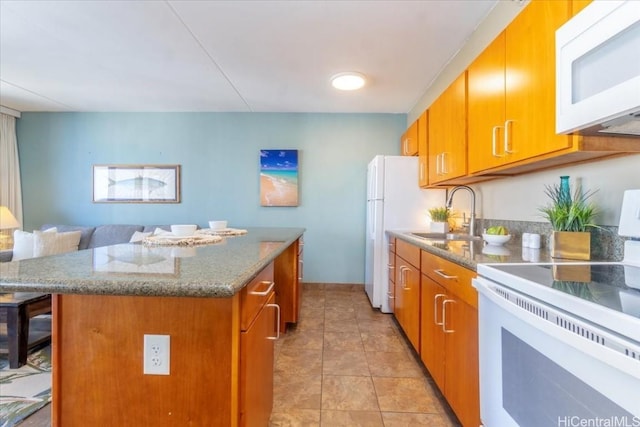 kitchen with brown cabinets, white appliances, a sink, and a center island