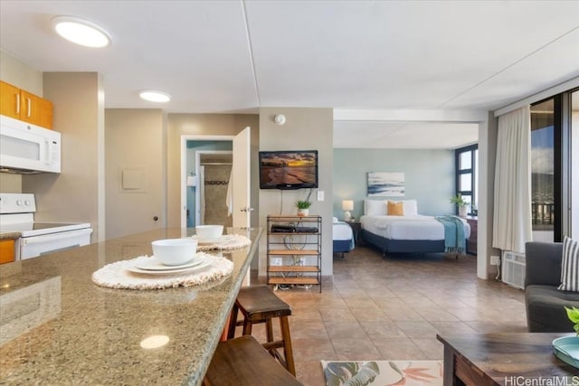 interior space with white appliances, open floor plan, a breakfast bar, light stone countertops, and light tile patterned flooring