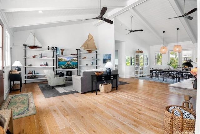 living area featuring high vaulted ceiling, ceiling fan, beamed ceiling, and wood finished floors