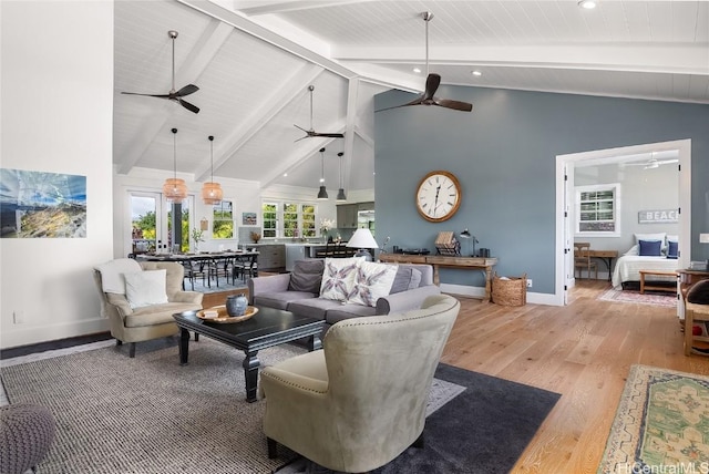 living area featuring light wood-type flooring, baseboards, a ceiling fan, and beamed ceiling