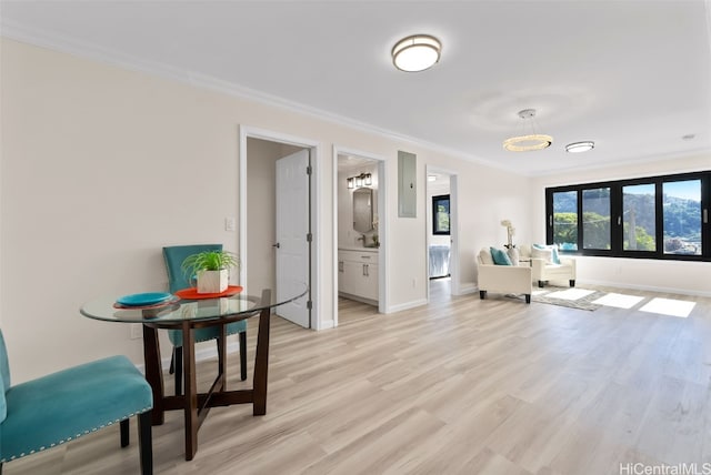 sitting room with ornamental molding, light wood-style floors, and baseboards