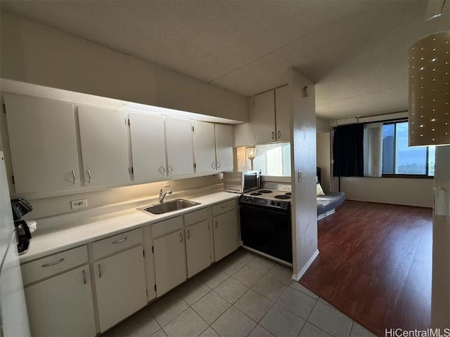 kitchen featuring stainless steel microwave, white cabinets, a sink, and electric range oven