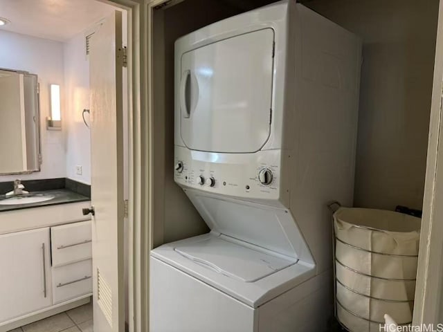 clothes washing area with stacked washer and clothes dryer, light tile patterned floors, a sink, and laundry area