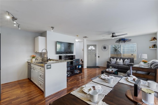 living area with a ceiling fan, visible vents, and dark wood finished floors